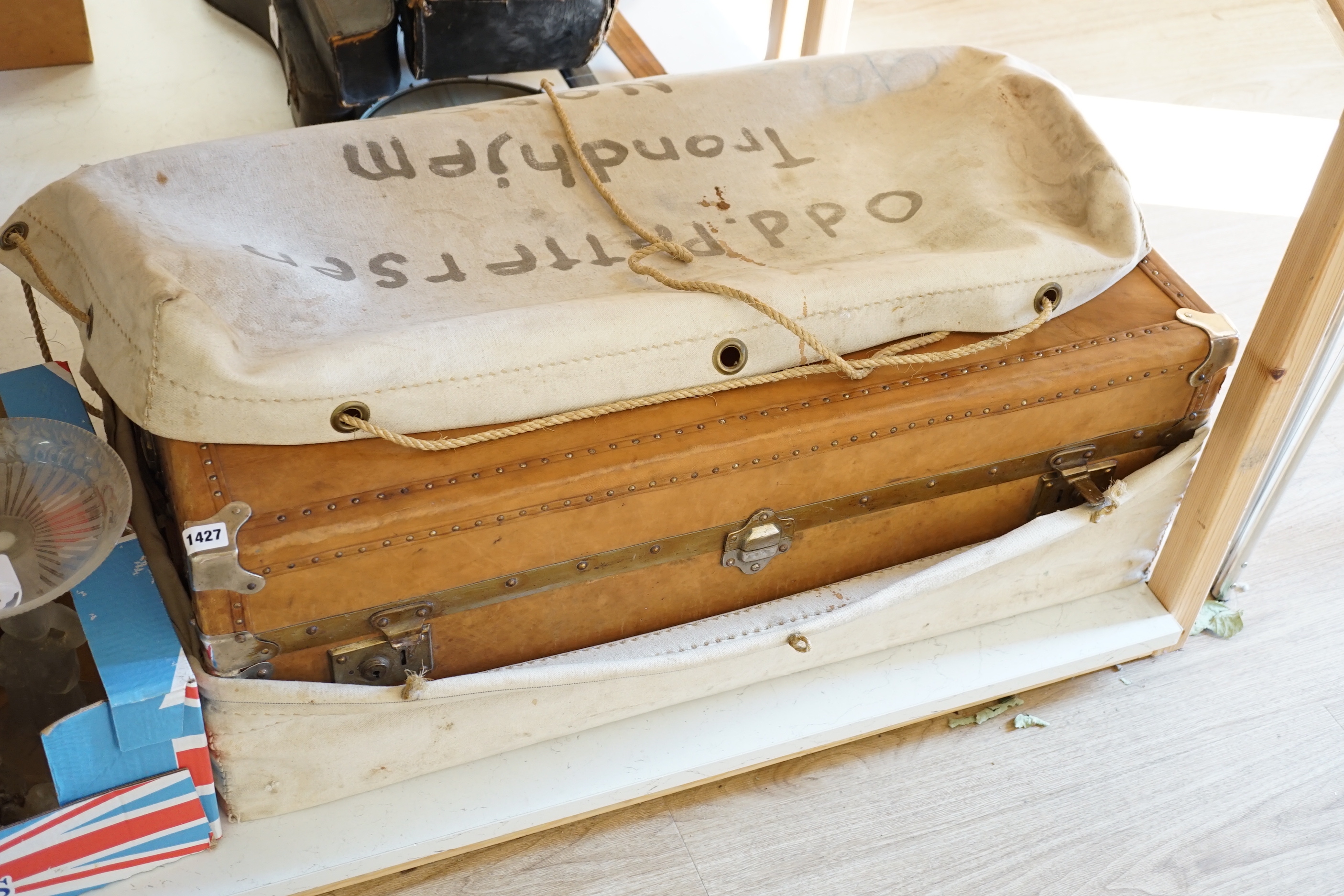 An early 20th century leather trunk, 90cm, in canvas outer wrapper